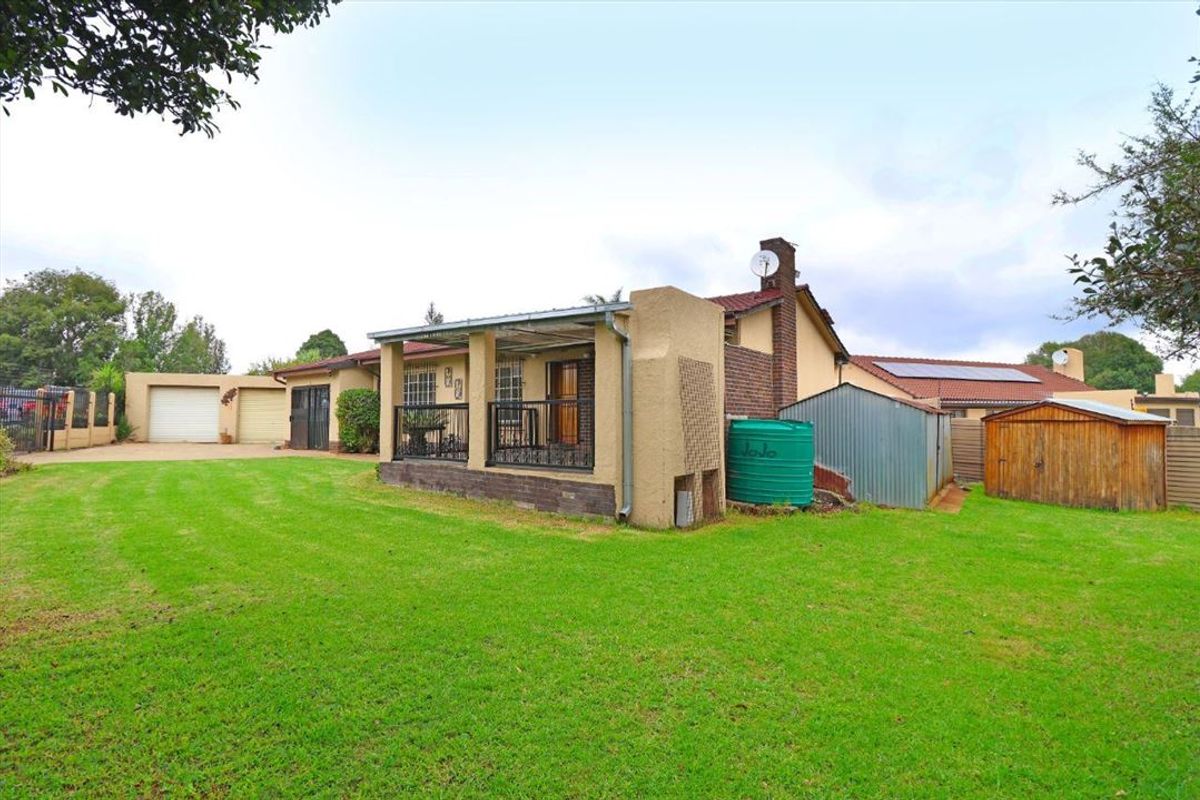 Rear view of the property featuring a covered patio, a large lawn, a water storage tank, and a detached storage shed.