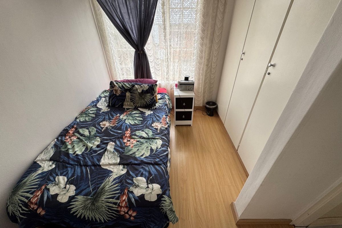 A compact bedroom featuring light-toned laminate flooring and built-in storage cupboards, providing a functional and efficient living space.