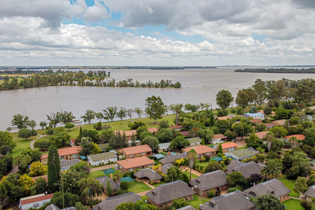 Aerial view of a residential estate featuring a mix of thatched and tiled roof homes situated along a scenic waterfront.
