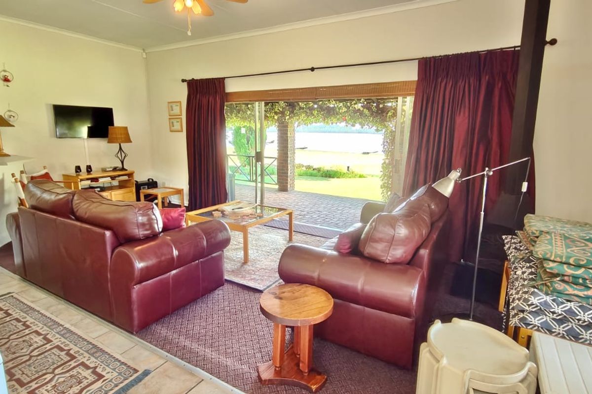Spacious living room featuring a wood-burning fireplace and large sliding glass doors that open onto a covered patio with scenic views.