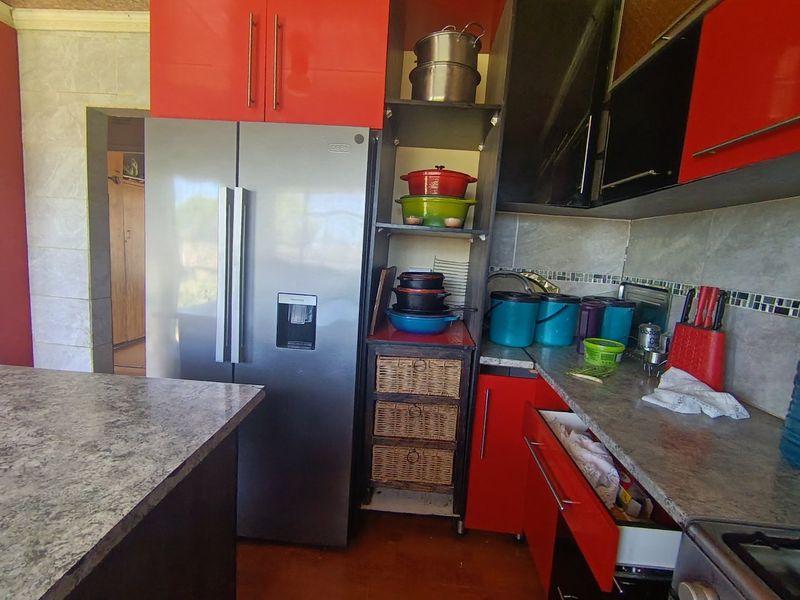 A functional kitchen featuring red cabinetry, stone-look countertops, and a tiled backsplash, providing ample storage and workspace for daily meal preparation.
