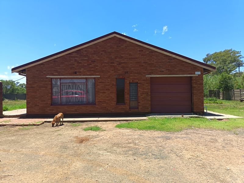 Front elevation of a face brick farm dwelling featuring a single garage door and security-barred windows.