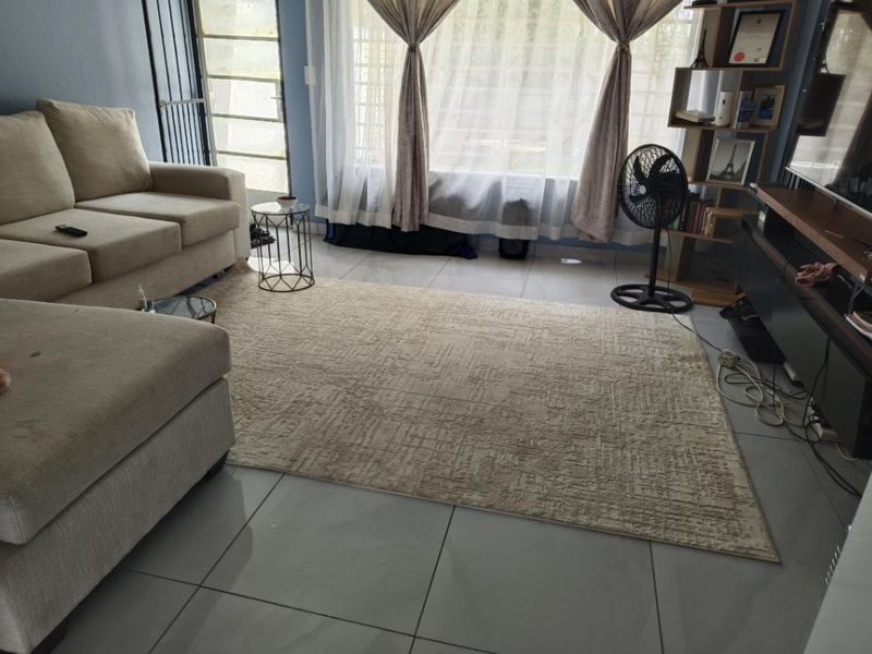 A living room featuring large format floor tiles, a sliding glass door with security gate, and natural light through sheer curtains.