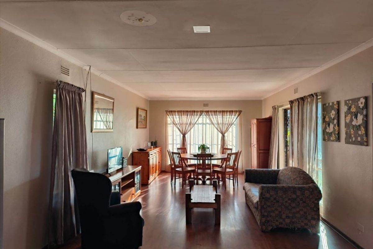 Spacious open-plan living and dining area featuring laminate flooring and large windows, providing a bright and versatile space for family gatherings.