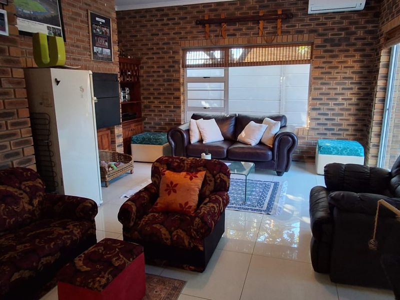 Spacious living room featuring exposed brick walls, tiled flooring, and large sliding glass doors providing natural light and access to the outdoors.