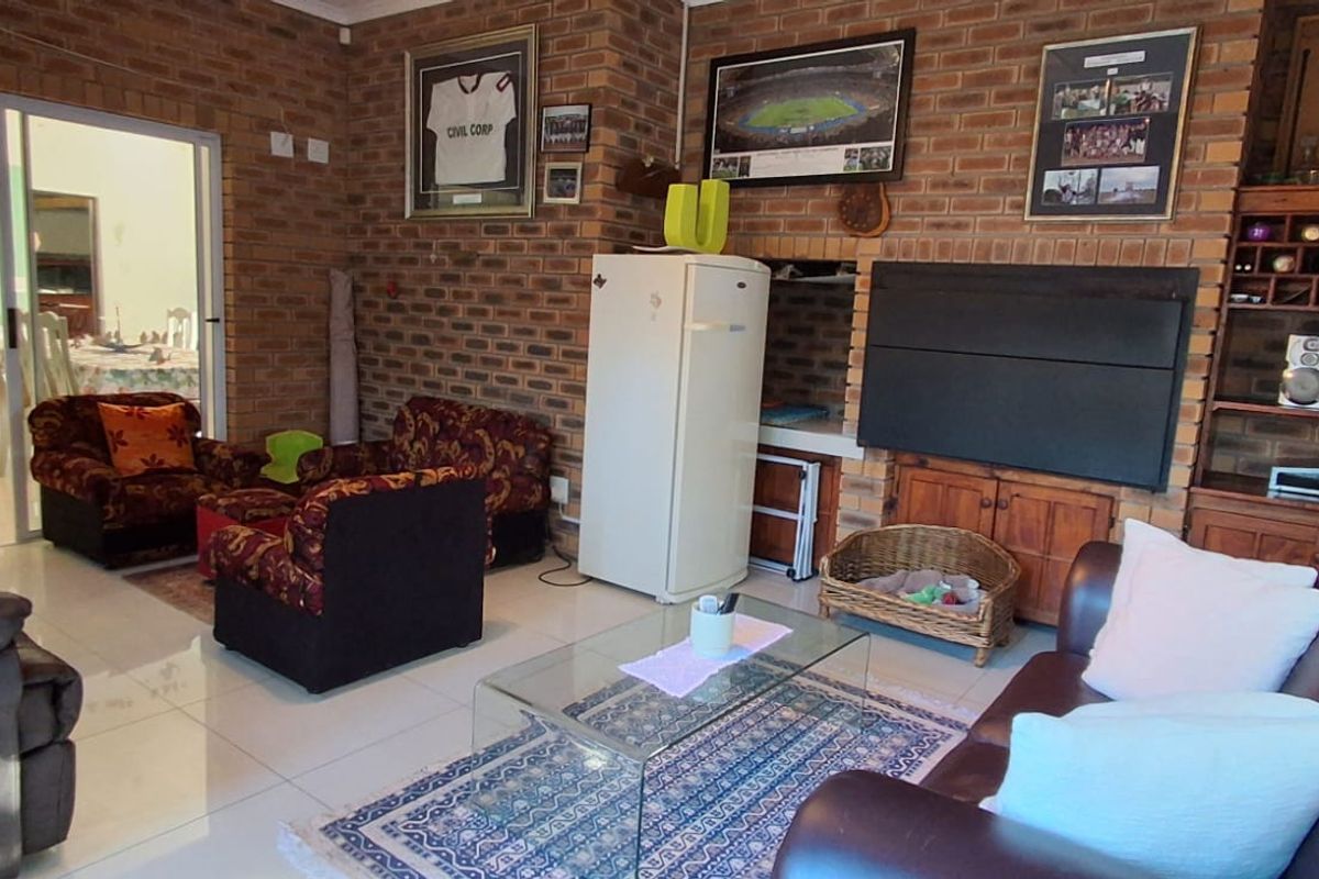 Spacious living room featuring exposed brick walls, a built-in fireplace, and tiled flooring, with direct access to the kitchen area.