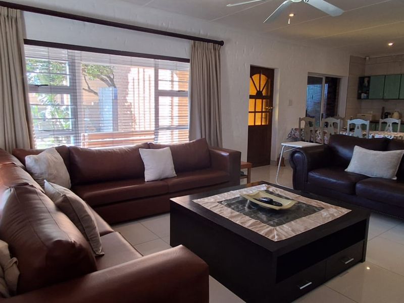 Spacious open-plan living area featuring tiled flooring, recessed lighting, and an integrated kitchen space with cabinetry.