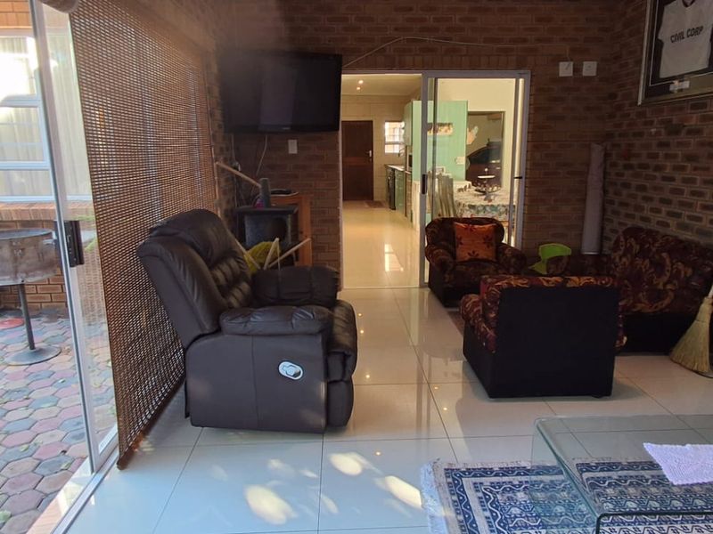 Enclosed patio area featuring exposed brick walls and tiled flooring, providing seamless access to the outdoor paved garden space.