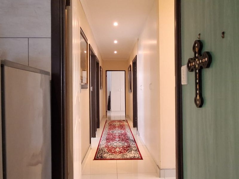 A well-lit interior hallway featuring tiled flooring and built-in storage cupboards, providing access to multiple rooms within the home.