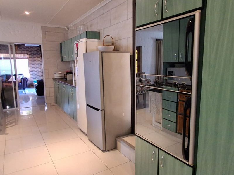 A functional kitchen featuring built-in cabinetry, tiled flooring, and a built-in oven, with a sliding door providing access to an adjacent living area.