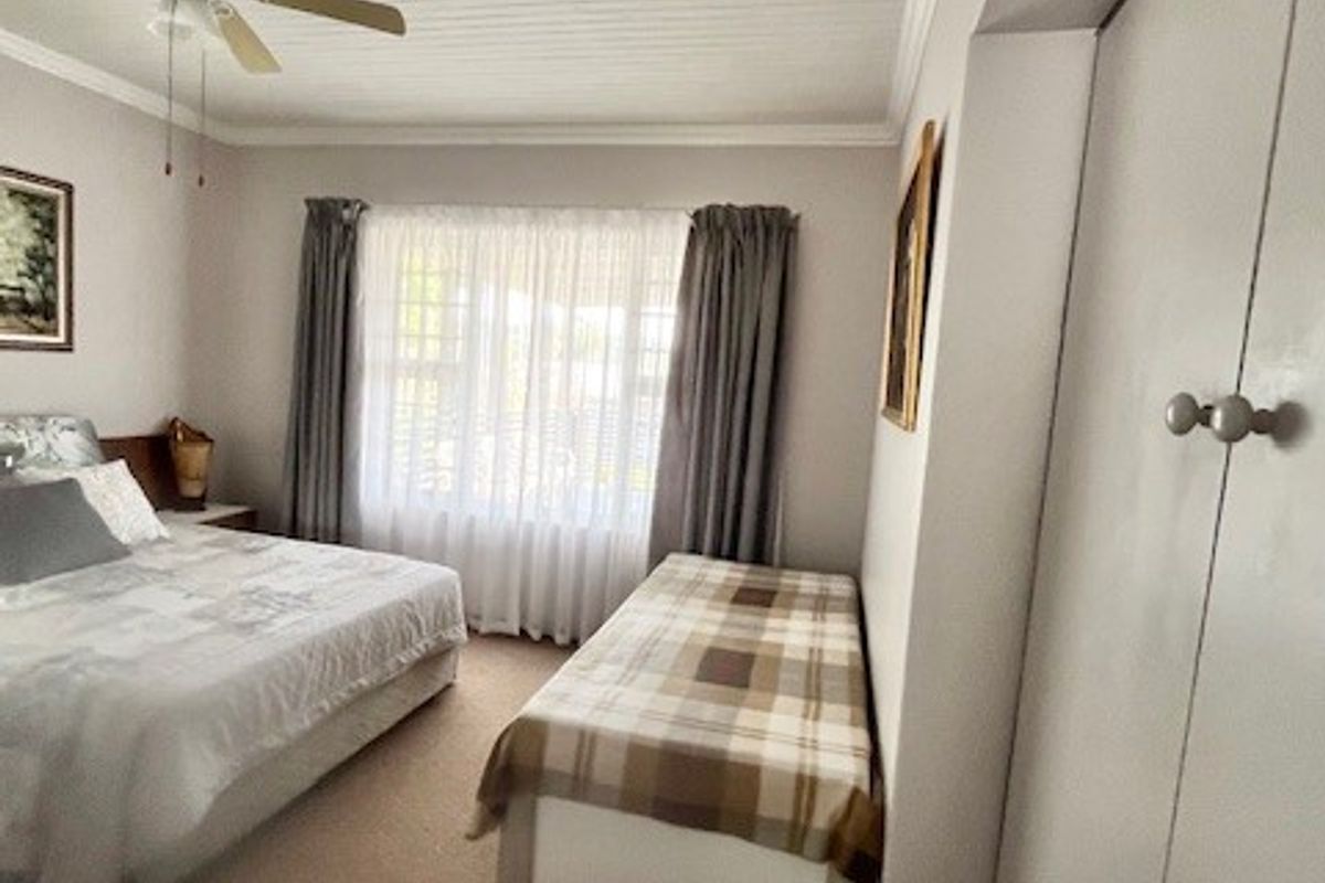 A bedroom featuring a tongue and groove ceiling, ceiling fan, carpeted flooring, and built-in cupboards for storage.