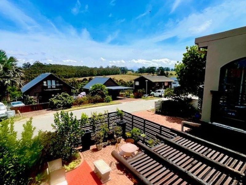 An elevated outdoor patio area featuring brick paving, a timber pergola, and timber slat fencing with views over the surrounding neighbourhood.