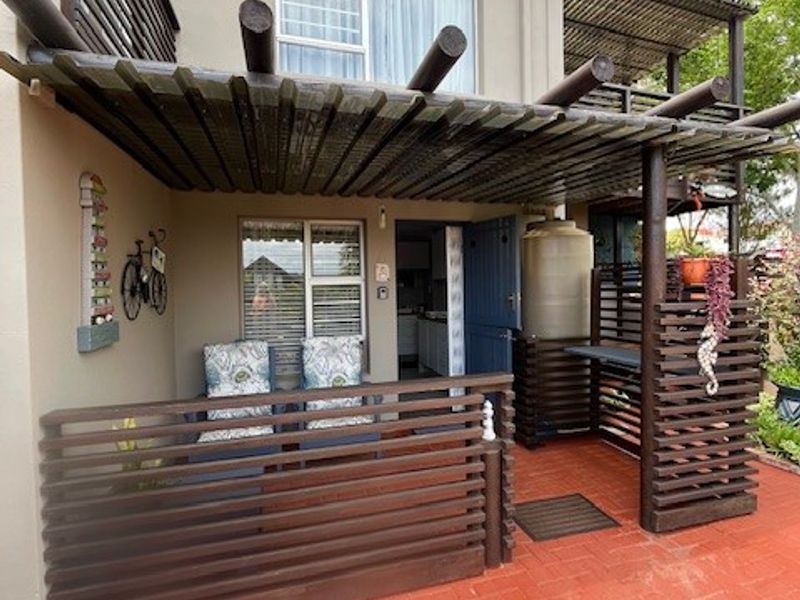 Covered patio area featuring a timber pergola, privacy screening, and a dedicated water tank, providing a functional outdoor space.