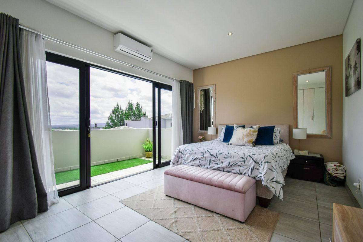 Spacious bedroom featuring tiled floors, a split-system air conditioner, and large sliding glass doors opening onto a private balcony with scenic views.