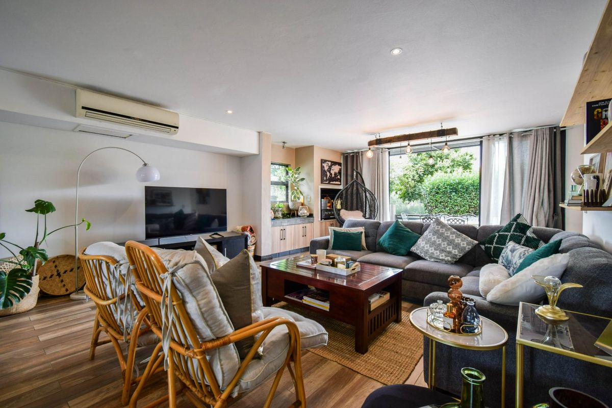 A well-maintained living room featuring timber-look flooring, recessed lighting, a split-system air conditioner, and direct access to the outdoor area via sliding glass doors.