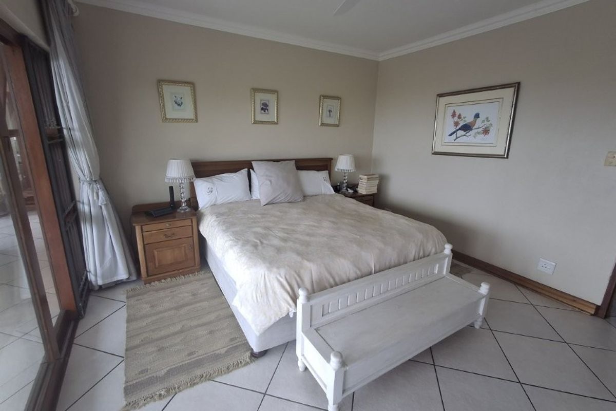 A spacious bedroom featuring neutral wall tones, tiled flooring, and sliding glass doors providing access to an outdoor area.