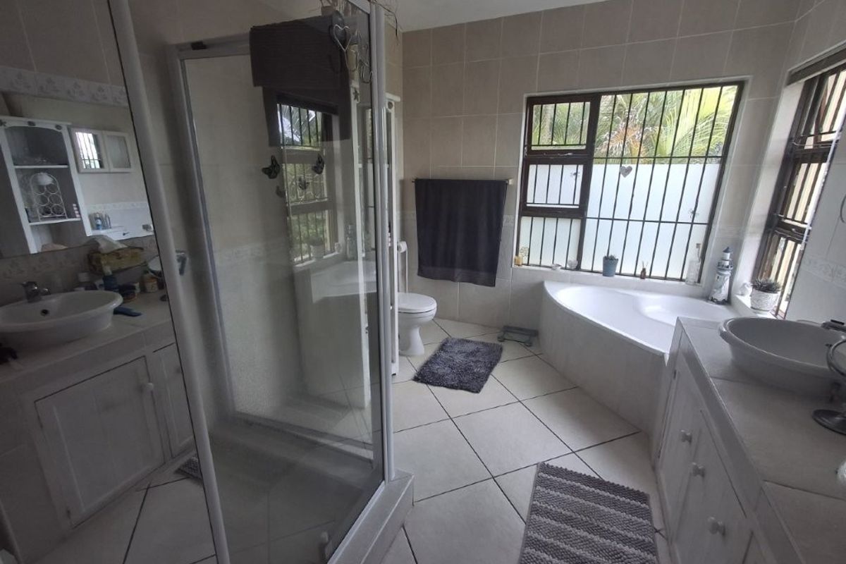 A spacious bathroom featuring a corner bathtub, a separate glass-enclosed shower, and dual vanity basins with built-in cabinetry.