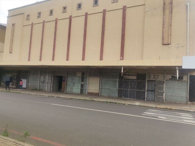 Front elevation of a commercial building featuring a weathered facade and security-gated storefronts along the street level.