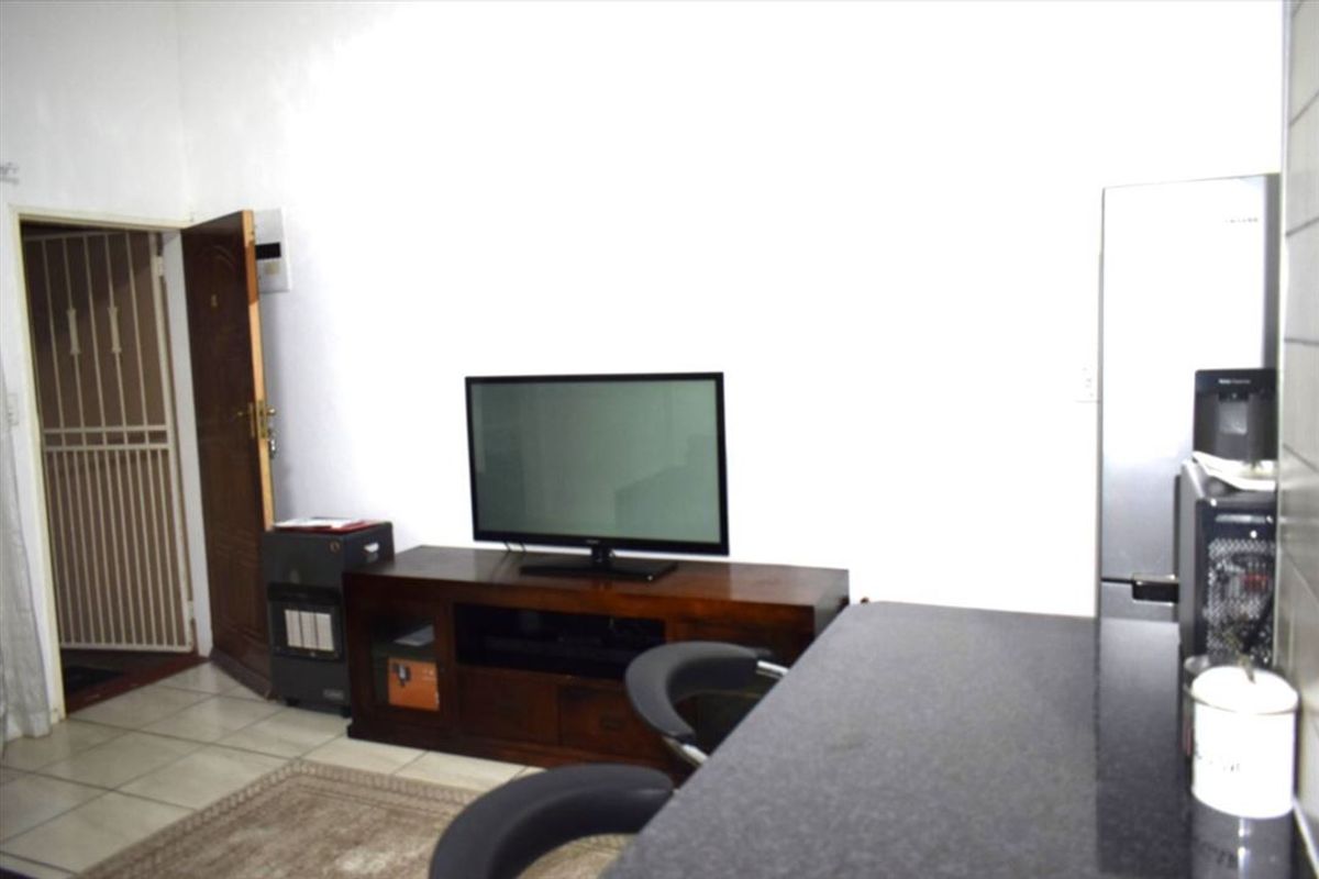 Open plan living area featuring tiled flooring and a breakfast bar with granite countertop, leading to a secure entrance.