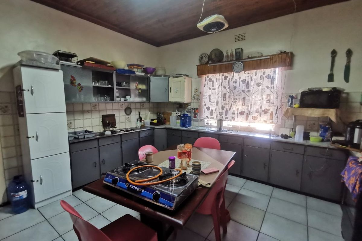 A dated kitchen featuring built-in cabinetry, tiled backsplash, and a timber ceiling, offering significant potential for modernization and renovation.