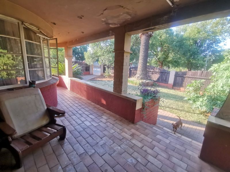 A covered patio area featuring brick paving and structural brick pillars, overlooking a private garden space.