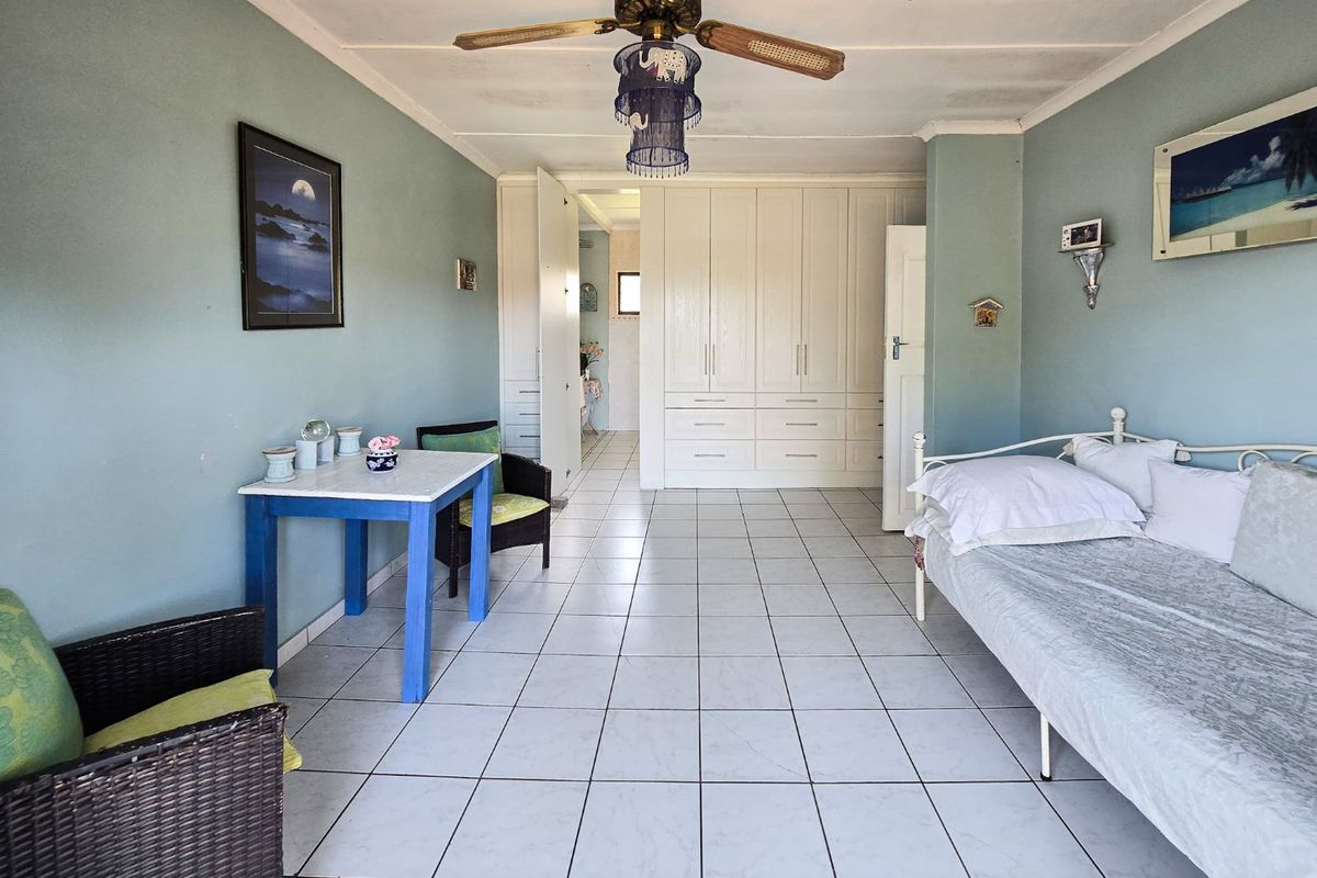 Spacious bedroom featuring built-in cupboards, tiled flooring, and a ceiling fan, offering a functional layout with potential for cosmetic updates.