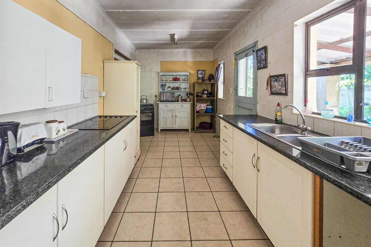 A functional galley-style kitchen featuring granite countertops, double basin sink, built-in cabinetry, and ceramic tile flooring throughout.