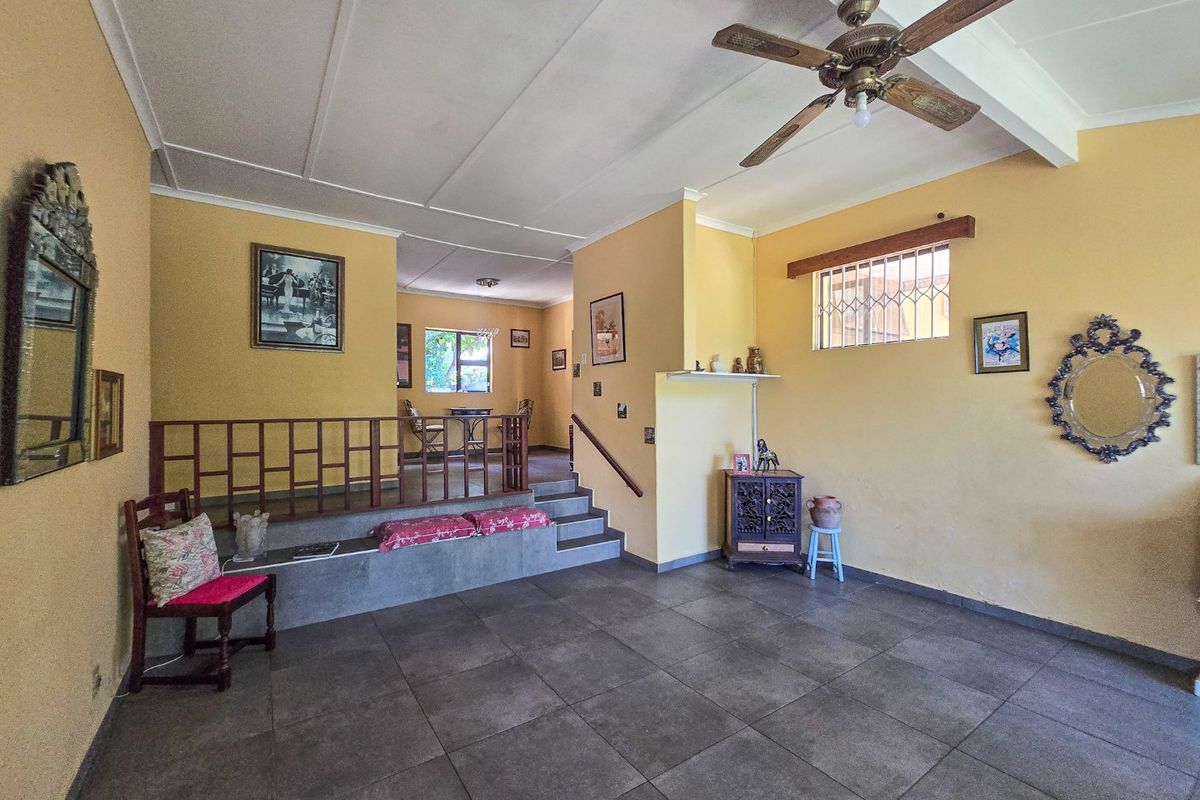 Spacious living area featuring tiled flooring, a raised platform with timber balustrade, and a ceiling fan, offering a versatile layout for family living.