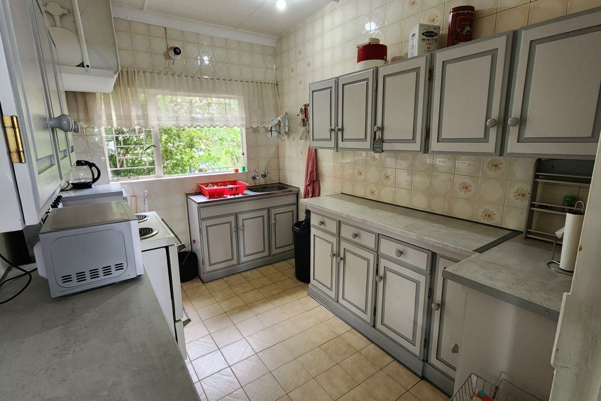 A functional kitchen featuring dated cabinetry, tiled backsplash, and laminate countertops, offering a practical layout with potential for modern cosmetic updates.