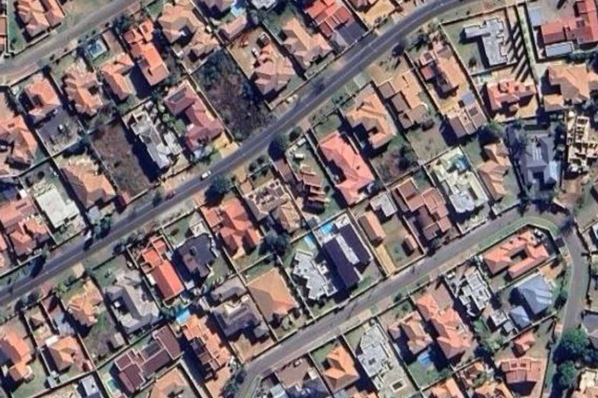 An aerial view of a residential neighborhood showing the layout of houses, streets, and surrounding property plots.