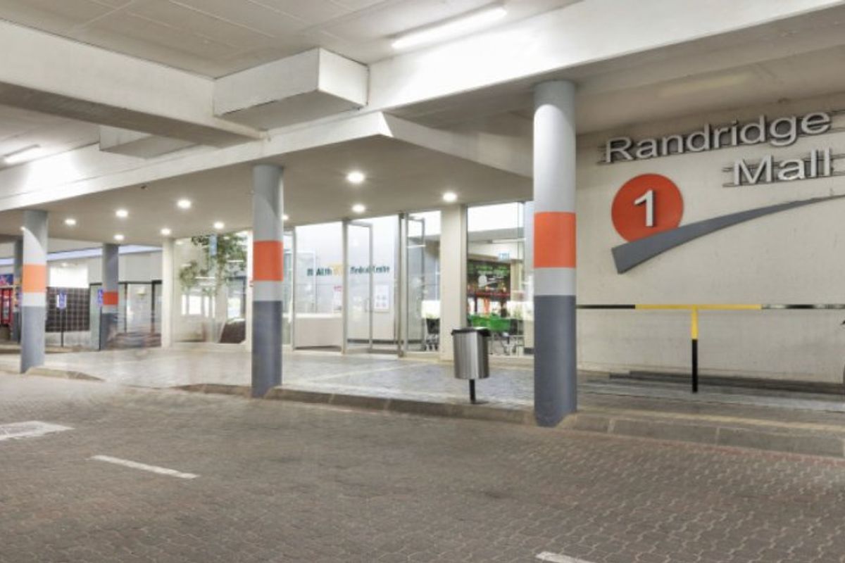 The front entrance of Randridge Mall featuring a covered paved driveway, structural columns, and clear glass access doors.