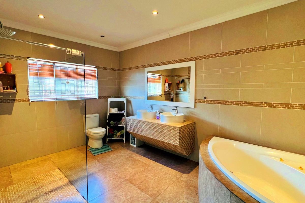 Spacious bathroom featuring a large walk-in glass shower, a corner bathtub, and a floating vanity with dual vessel sinks.