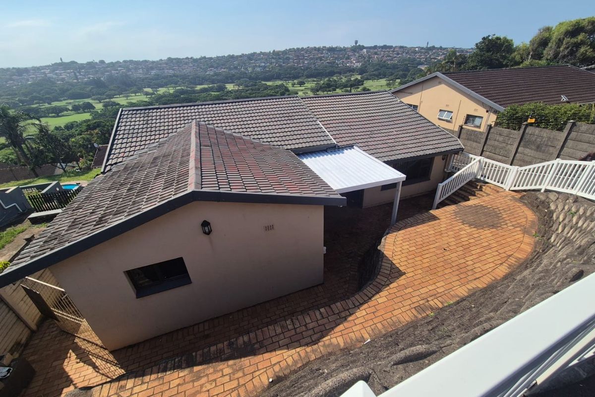 Aerial view of the property showing the tiled roof, paved rear patio area, and surrounding landscape with a scenic outlook.