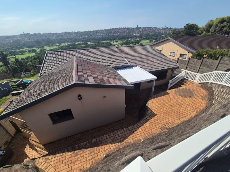 Aerial view of the property showing the tiled roof, paved rear patio area, and surrounding landscape with a scenic outlook.