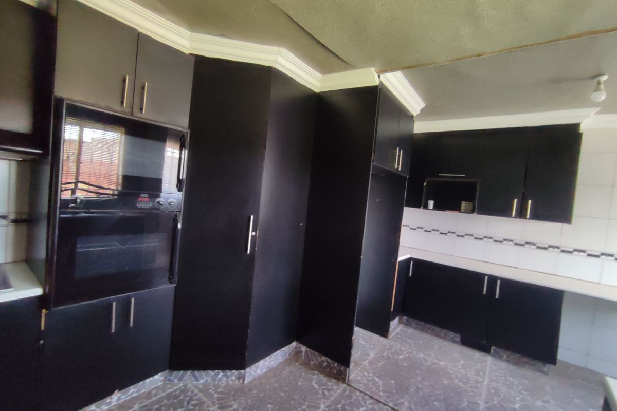 A kitchen featuring dark cabinetry, built-in oven, tiled backsplash, and laminate countertops, requiring minor ceiling finishing to complete the space.