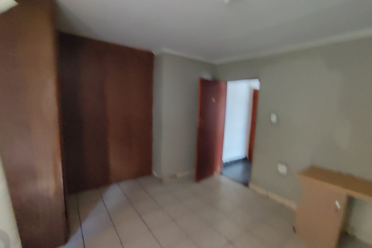 A vacant bedroom featuring tiled flooring and built-in wooden cupboards, offering a blank canvas for personalization.
