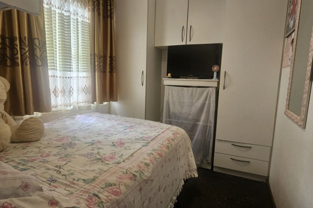 A functional bedroom featuring a built-in wardrobe and a window, providing essential storage and natural light.