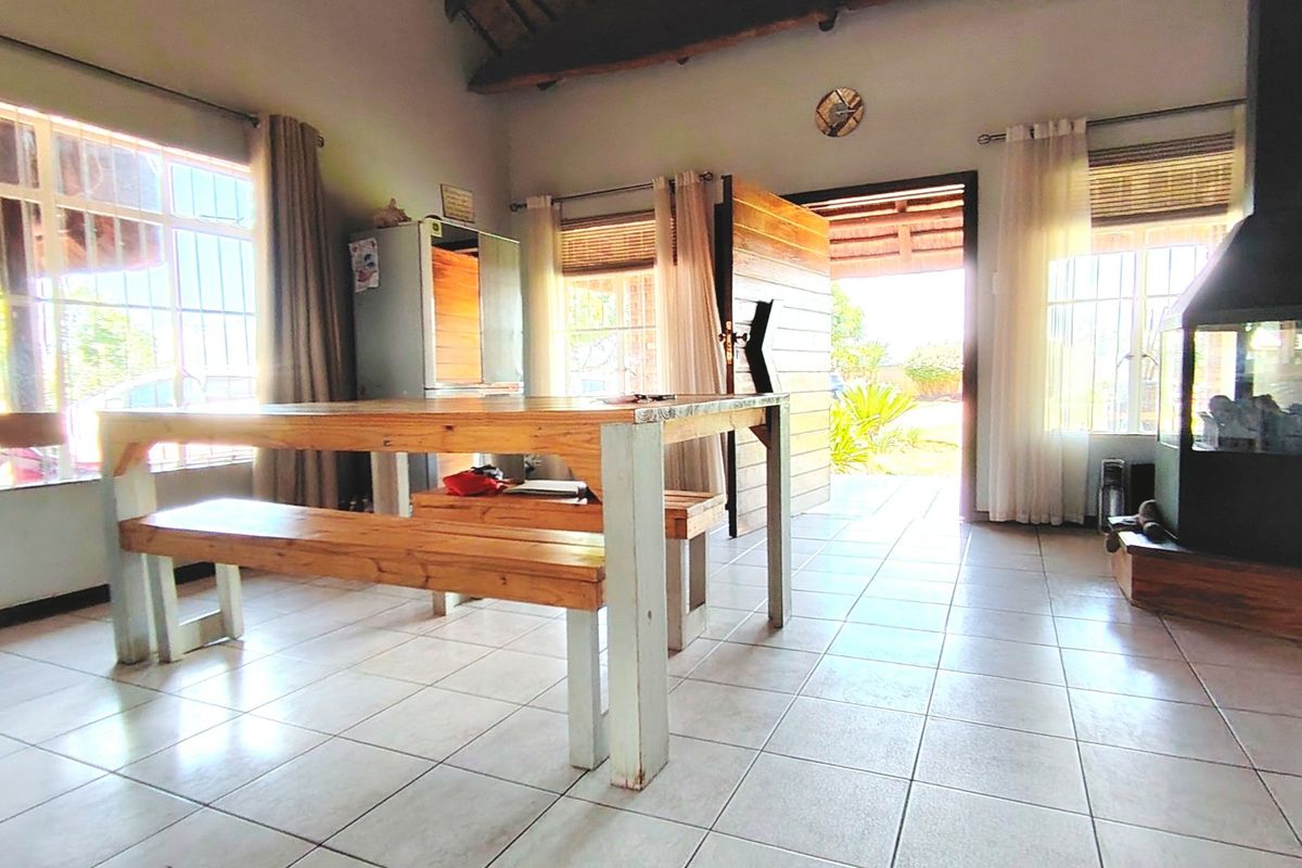 Living area featuring tiled flooring, exposed timber roof beams, and a prominent freestanding fireplace, with direct access to the outdoor area.