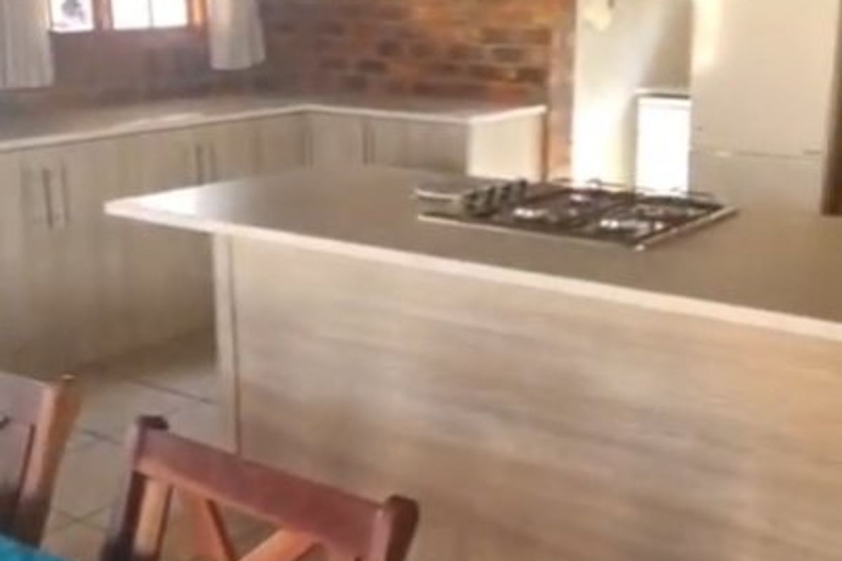 A kitchen featuring exposed brick walls, a central island with a gas hob, and light-toned cabinetry, offering a rustic yet functional cooking space.