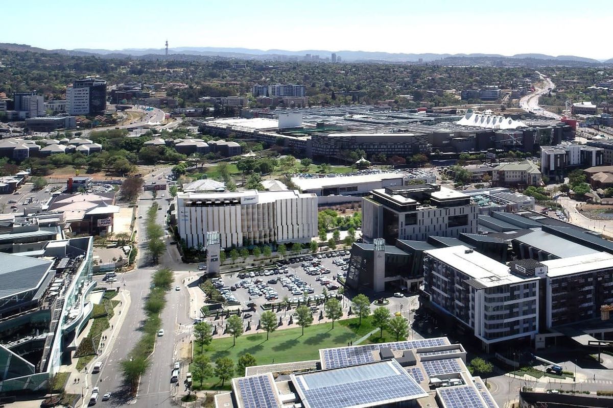 An expansive aerial view of a commercial business district featuring modern office buildings, extensive parking facilities, and integrated solar energy infrastructure.