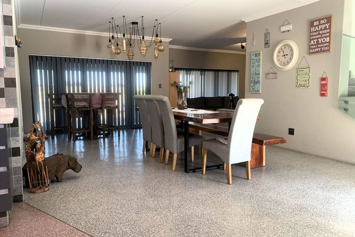 Spacious open-plan living and dining area featuring durable epoxy flooring, modern pendant lighting, and large sliding glass doors that provide ample natural light.