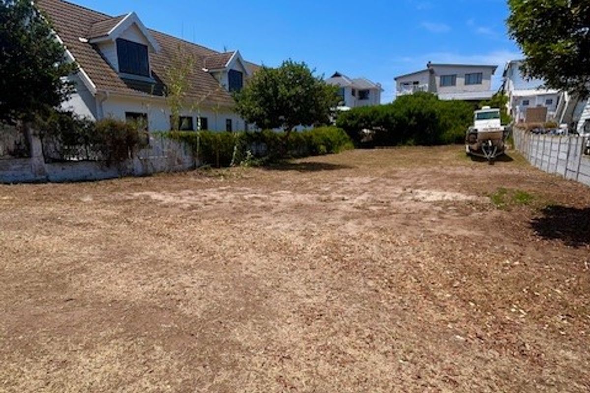 A vacant residential plot of land featuring established boundary fencing and mature trees, offering a clear space for future development.