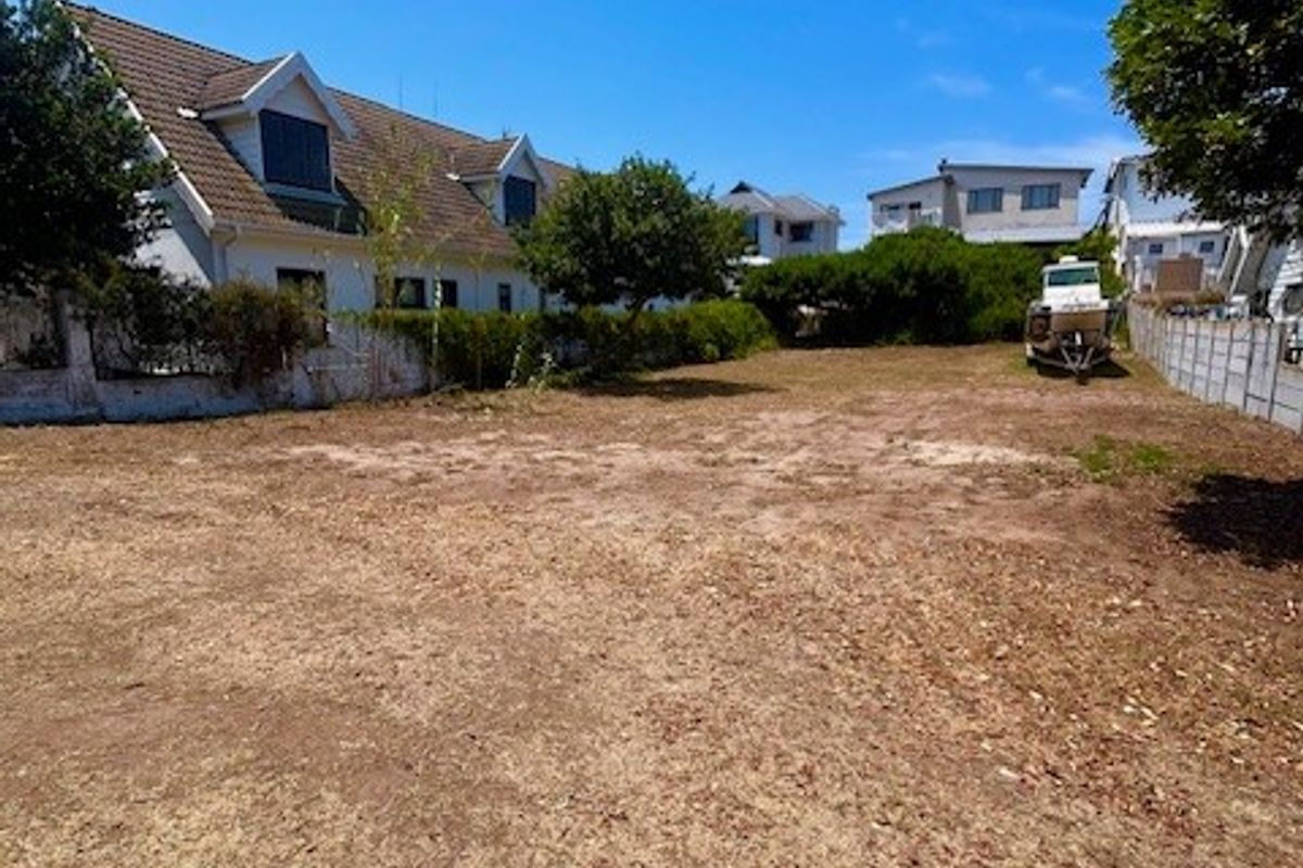 A vacant residential plot of land featuring boundary walls and surrounding residential properties.