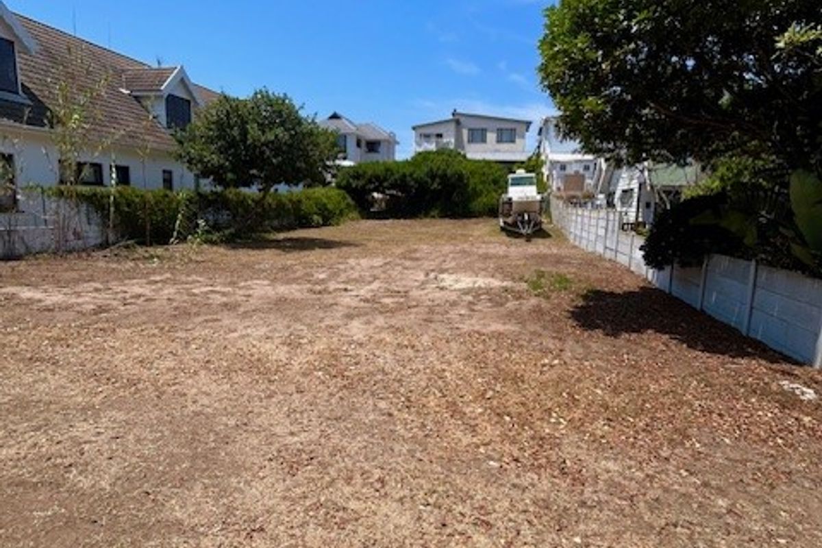 A vacant residential plot featuring boundary fencing and established trees, offering a clear space ready for development.