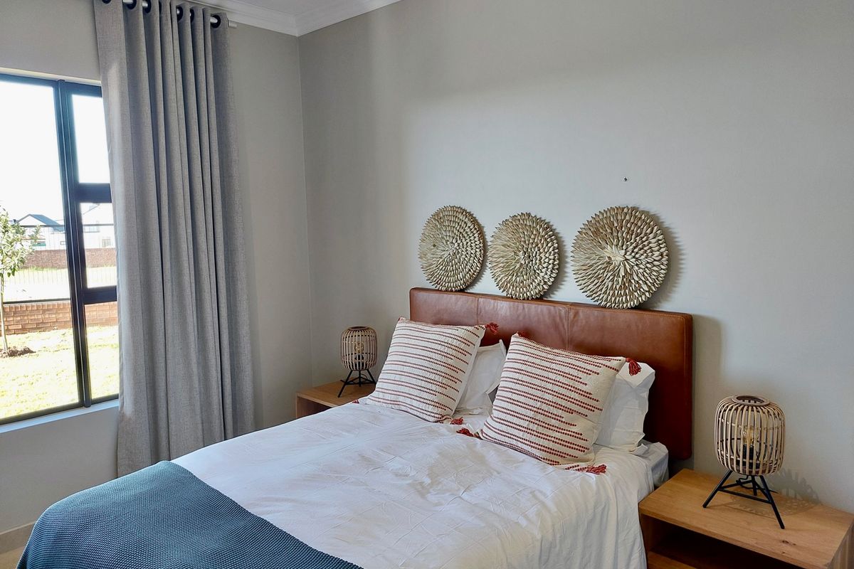 A well-maintained bedroom featuring neutral wall tones, modern aluminium window frames, and decorative cornice detailing, offering a bright and comfortable living space.