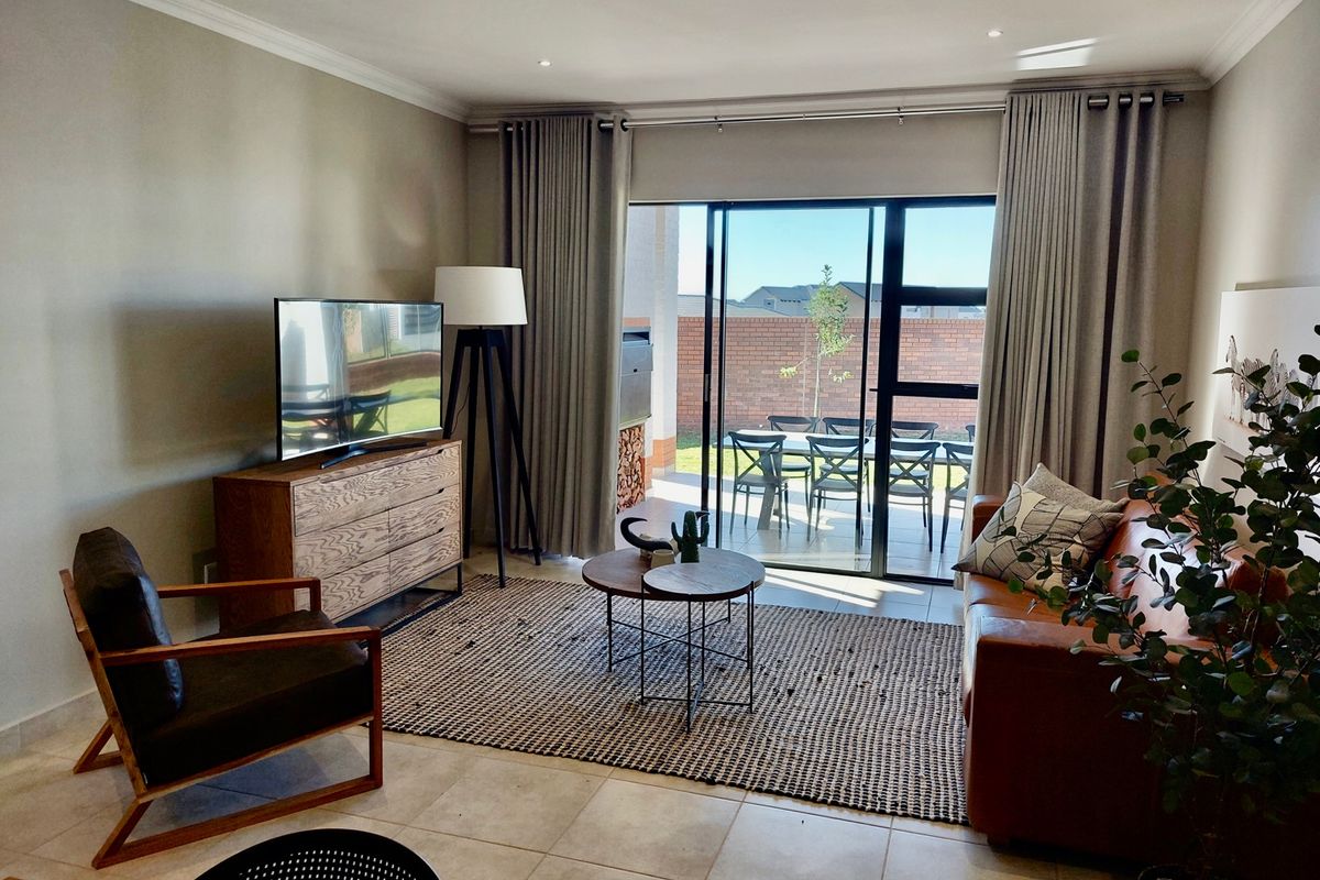 A well-maintained living room featuring tiled flooring, recessed lighting, and large sliding glass doors that provide seamless access to the outdoor patio area.