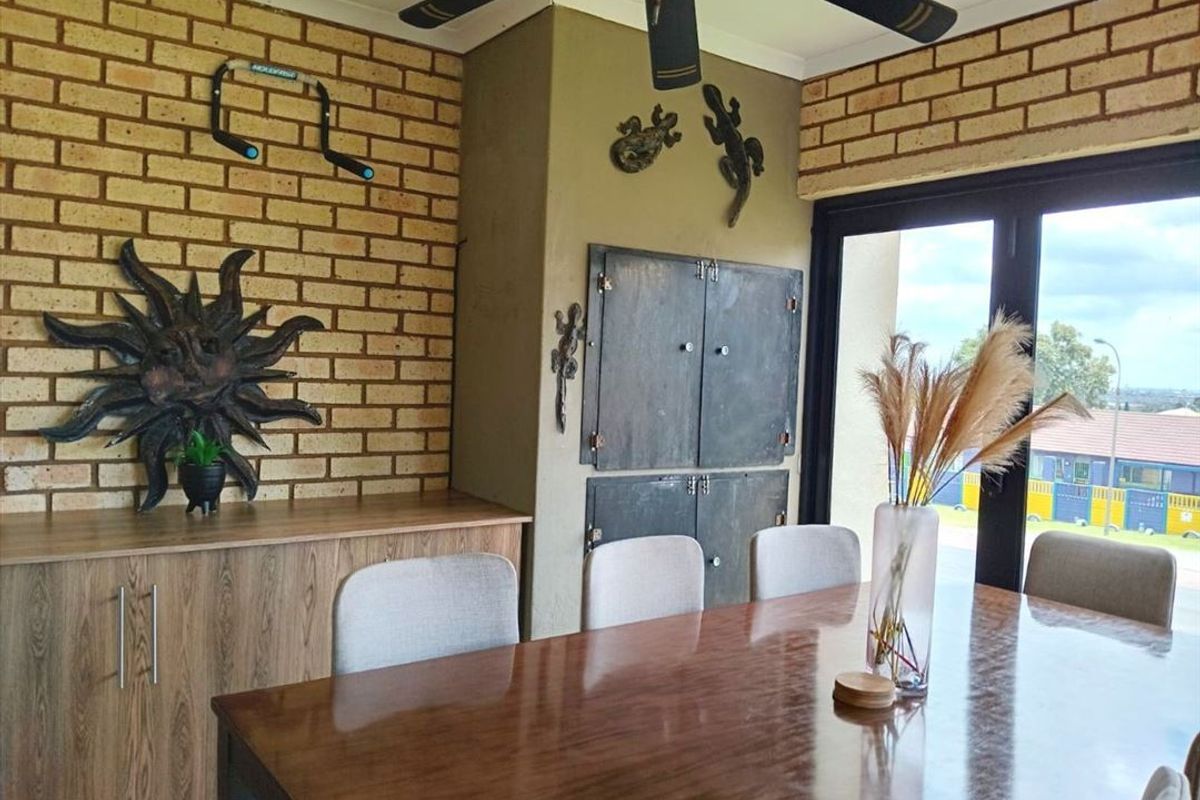 Dining area featuring an exposed brick feature wall, built-in storage cabinetry, and large sliding glass doors providing natural light.