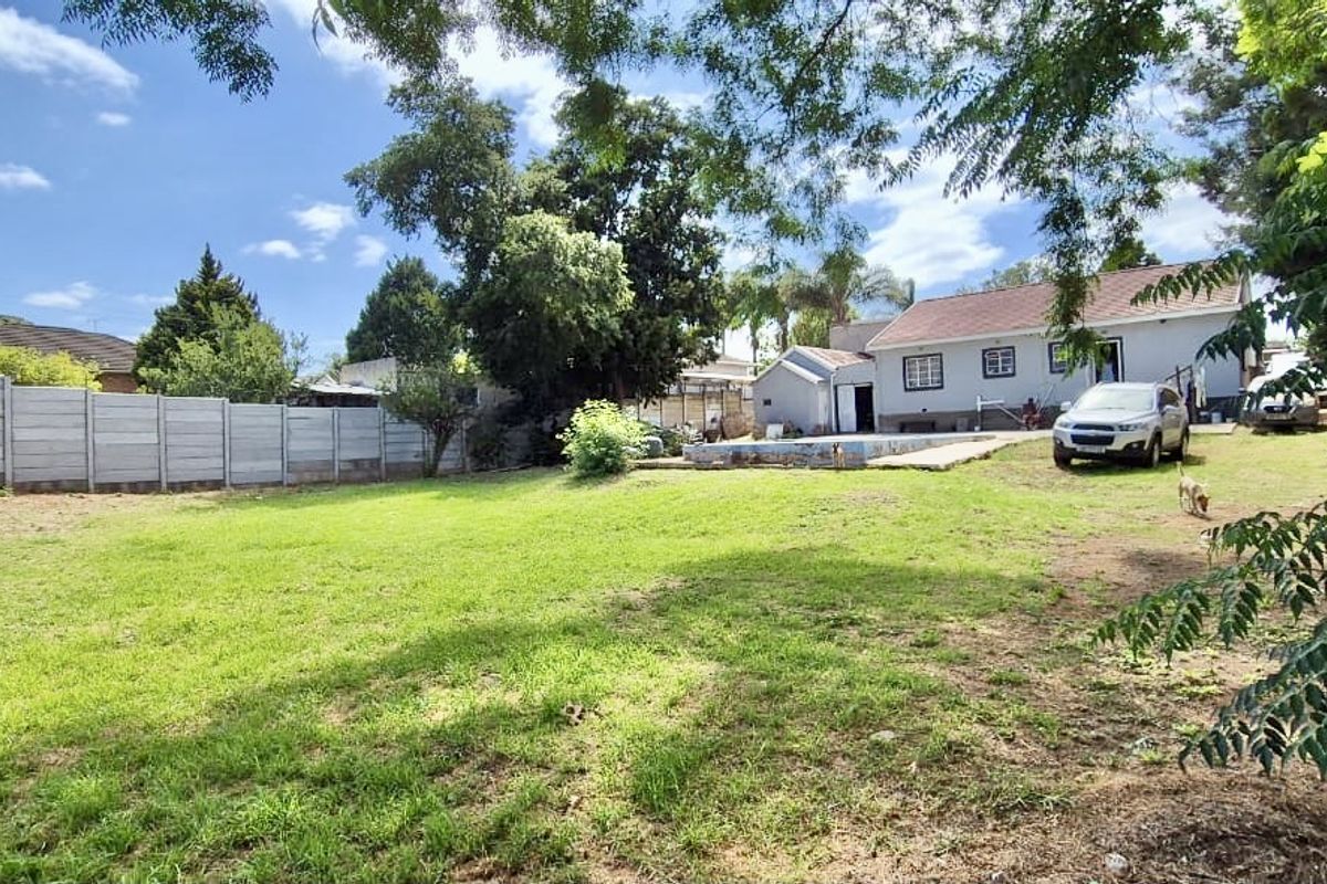 Spacious rear garden featuring a large lawn, precast concrete boundary wall, and an existing swimming pool area.