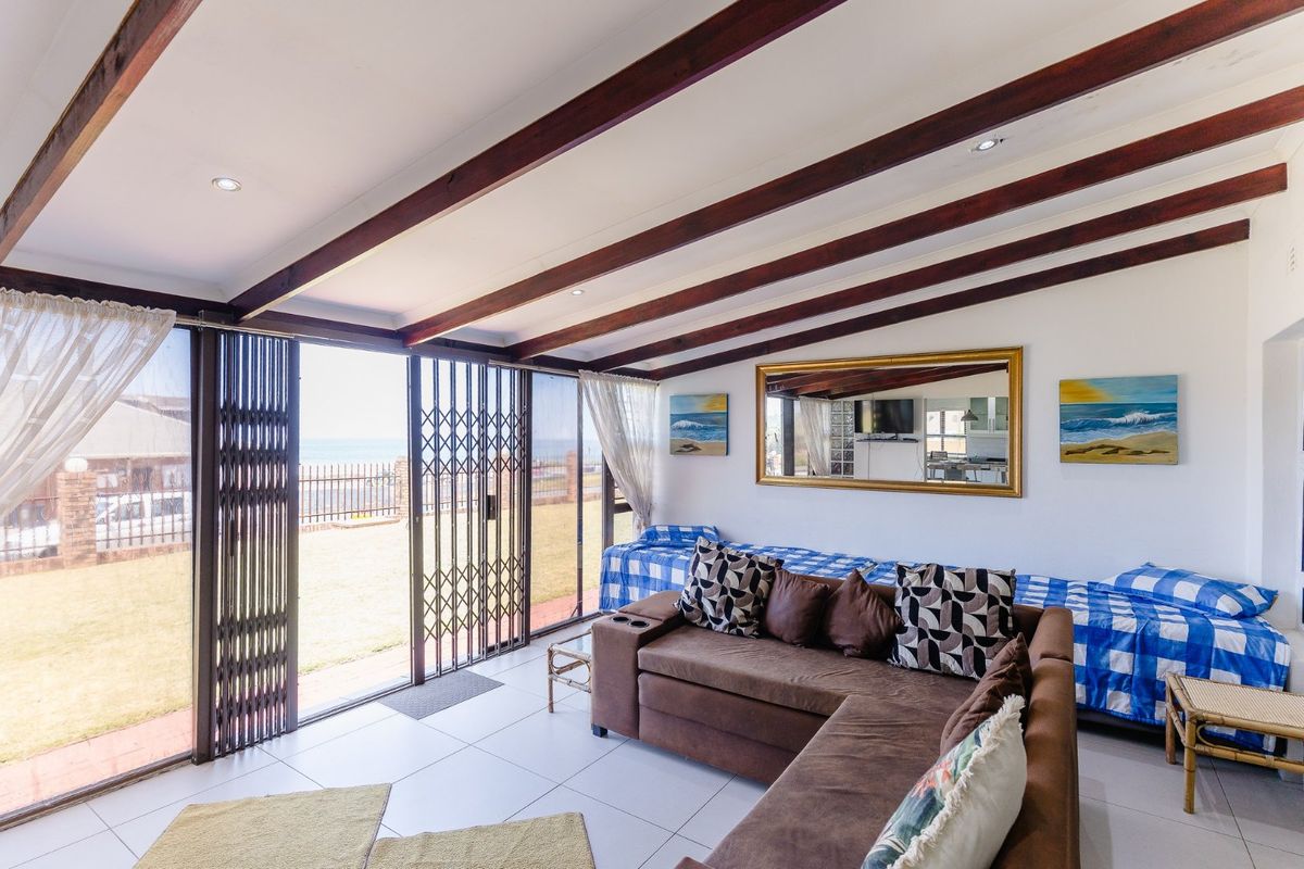 Bright living area featuring exposed timber ceiling beams, tiled flooring, and large sliding doors providing direct access to the outdoor area.