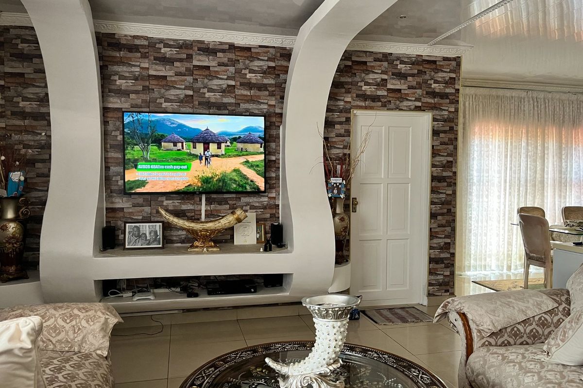 Living room featuring a prominent stone-cladding feature wall with a built-in media unit, tiled flooring, and recessed ceiling lighting.
